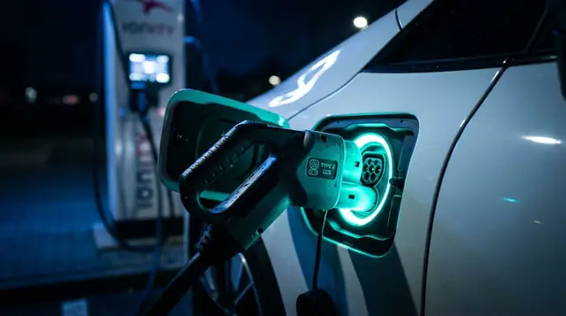 Elektrikli araca takılı CCS2 şarj kablosu ve turkuaz ışıklı şarj portu